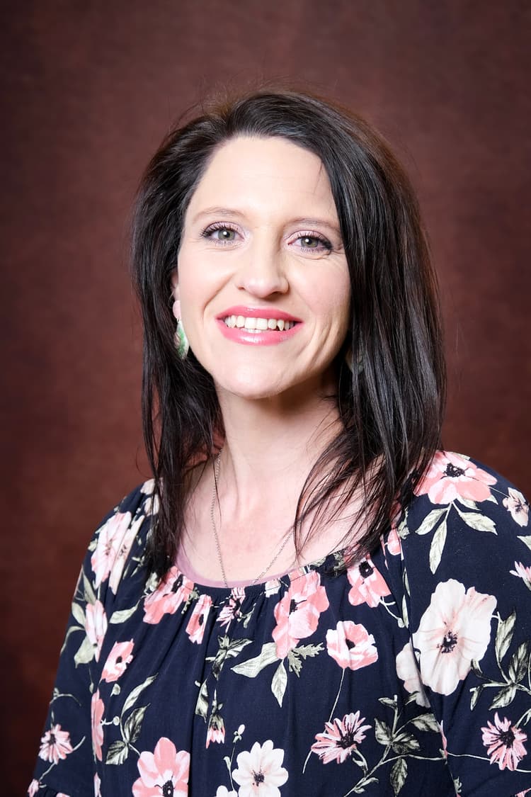 A woman in a floral top smiling for a picture