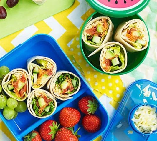 A table topped with plates of food and containers of fruit