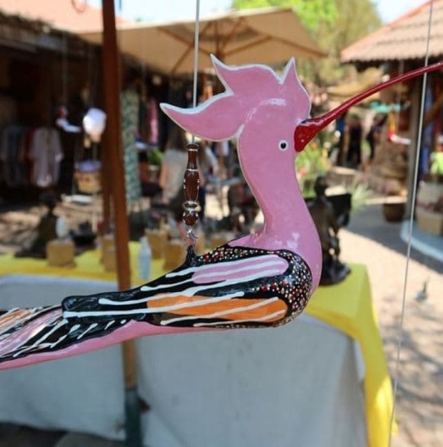 A pink bird is hanging from a string