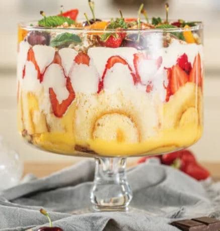 A trifle with fruit and whipped cream in a glass dish