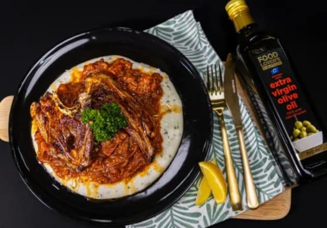 A plate of food on a table next to a bottle of olive oil